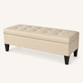 Studio three-quarter | Beige flip-top storage bench showing tufted lid, piped seam, and tapered espresso legs