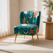 Warm three-quarter | teal-blue floral velvet armless slipper chair from the opposite angle beside a round oak table