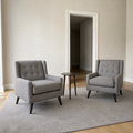 In scale | two gray tufted armchairs beside a fully open interior doorway with a dark hallway beyond