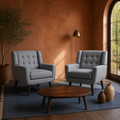 Terracotta room | two gray tufted armchairs on a plain indigo rug with an arched garden door and low walnut table