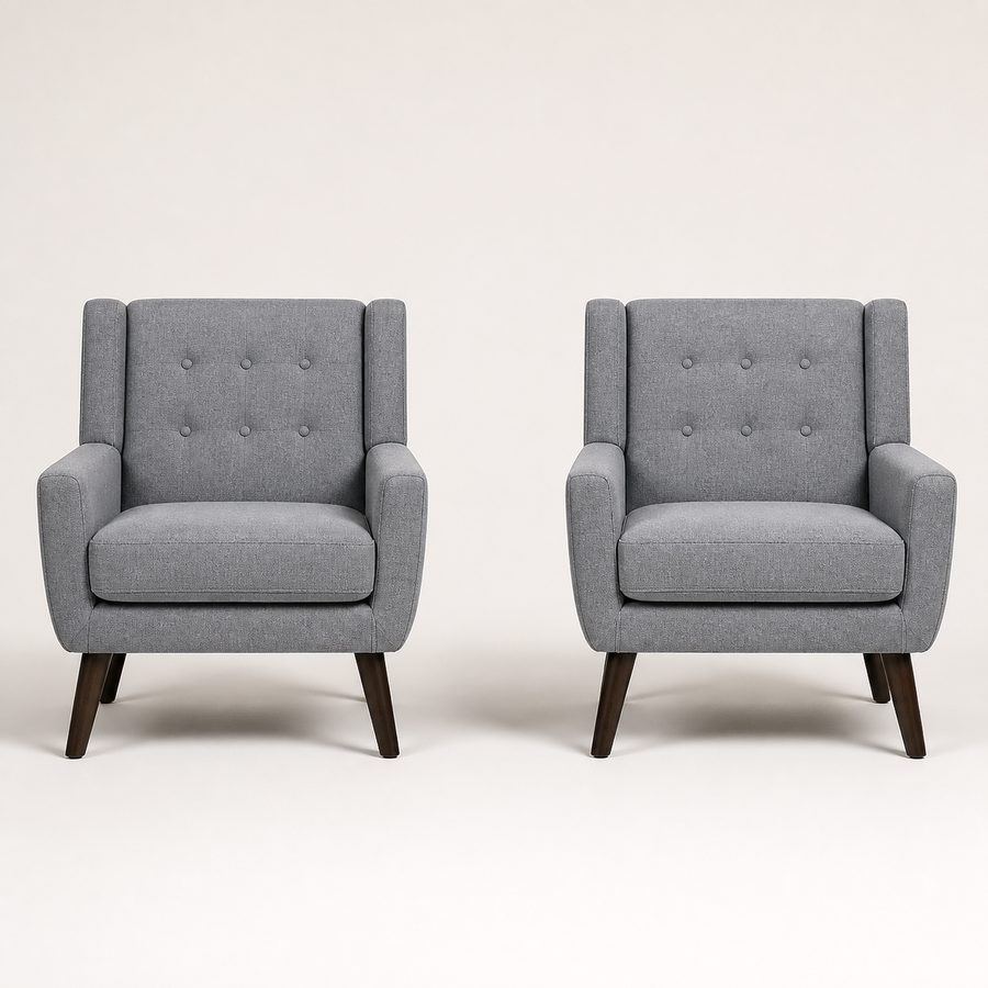 Front | pair of gray tufted armchairs straight on against a warm white studio sweep with six-button backs and dark splayed legs