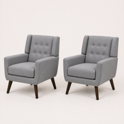 Studio angle | pair of gray tufted armchairs from a left-front three-quarter view on a warm white sweep