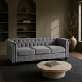 Room | Light gray velvet Chesterfield sofa in a dark olive library room with arched shelves, a travertine table, and a plain charcoal rug