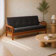 Room | Opposite front three-quarter view of the charcoal-gray futon in a soft-greige living room with oak table, lamp, and plant