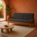 Room | Charcoal-gray futon in a terracotta garden room with an arched courtyard opening, plain rug, and low wood table