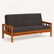 Studio | Left front three-quarter studio view of the charcoal-gray futon with the near slatted arm and bench-seat depth visible