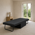 Scale | flat dark charcoal convertible sleeper beside an uncropped glass doorway in a compact guest room