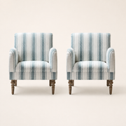 Front | straight-on studio view of two matching arched armchairs with recessed arms and dark turned legs