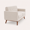 Studio | Side and rear profile of the beige linen loveseat with tapered wood legs