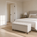 Scale view | warm beige tufted storage ottoman at the foot of a bed beside a full-height doorway
