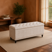 Terracotta living room | warm beige upholstered storage ottoman with a tufted lid, channel stitching and dark turned legs