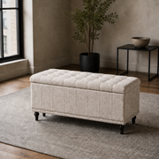 City loft | warm beige upholstered storage ottoman with a tufted lid, channel stitching and silver nailhead trim