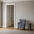 Scale | patterned club chair beside a fully visible interior doorway with a small round side table