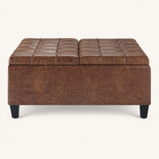 Studio front | square umber-brown faux leather ottoman with two tufted lid panels and four tapered dark legs on a warm-white ground