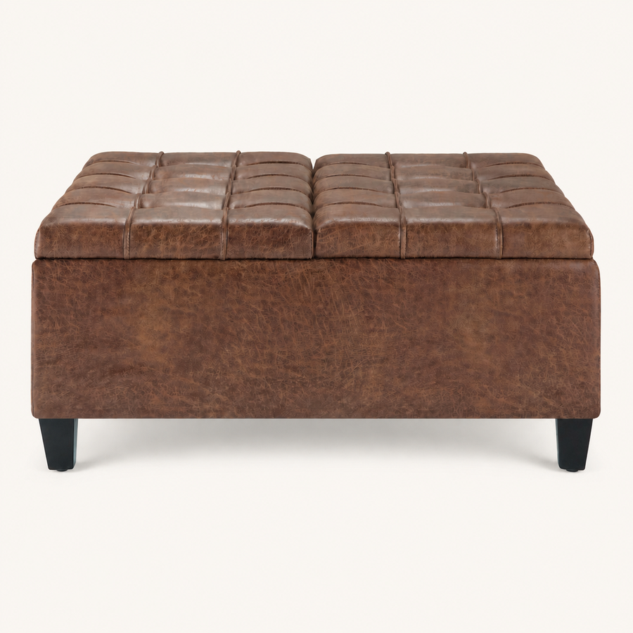 Studio front | square umber-brown faux leather ottoman with two tufted lid panels and four tapered dark legs on a warm-white ground