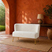 In a room | ivory velvet channel-tufted armless loveseat with gold hairpin legs in a terracotta garden room
