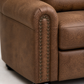 Hardware macro | close view of two rows of dark bronze-brown nailheads on a rolled brown faux-leather arm