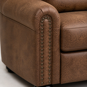 Hardware macro | close view of two rows of dark bronze-brown nailheads on a rolled brown faux-leather arm