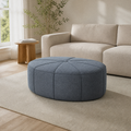 In a room | warm living room with a slate gray-blue oval tufted ottoman in front of a cream sofa
