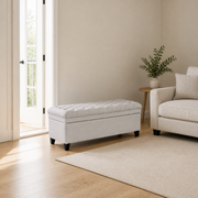 Scale | closed light gray polyester storage ottoman beside an uncropped floor-to-ceiling doorway, showing its real size and tapered dark wood legs