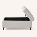 Open | side studio view of the light gray polyester storage ottoman with its flip top open, black-lined storage cavity, dark metal lid support, and plain side panel