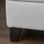 Texture close-up | light gray polyester slub weave on the plain upholstered side panel with a tapered dark wood leg