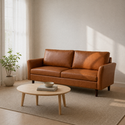 Living room angle | Mid-brown faux leather sofa from a three-quarter angle with a pale oak coffee table