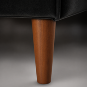 Hardware | close-up of tapered warm-brown wood sofa leg at the black velvet base