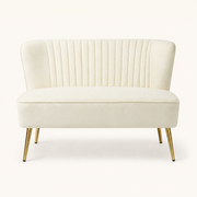 Front | Ivory velvet armless loveseat with channel tufting and four gold metal legs on a clean studio ground