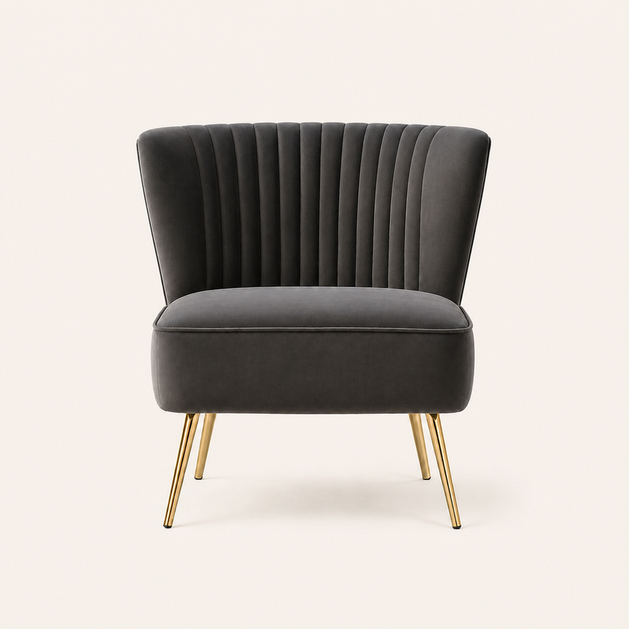 Front | Grey velvet accent chair with a flared channel-tufted back and four tapered gold legs on a clean studio ground