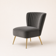 Studio angle | Grey velvet channel-tufted accent chair from a three-quarter view with its piped seat and gold legs