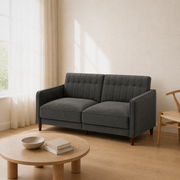 Angle | The same gray velvet sofa from three-quarters near a window, square arms and brown tapered legs