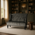 In a room | charcoal gray velvet diamond-tufted wingback loveseat in a deep olive library