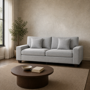 Room | Light gray chenille sofa in a warm stone loft beside a black-framed window and dark wood coffee table