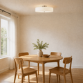 In a room | white drum semi-flush mount hanging close to the ceiling over a round oak dining table
