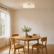 In a room | white drum semi-flush mount hanging close to the ceiling over a round oak dining table