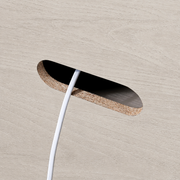 Cable management close-up | rounded rear routing aperture, pale wood-grain panel edge, dark opening, and white cable
