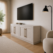 Warm room angle | right-corner view showing the four-door TV stand, side depth, pale oak floor, lamp, chair, and plain rug