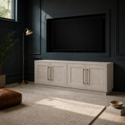 In a blue-green paneled media room | Alder White TV stand beneath a wall-mounted TV with cool diagonal window light
