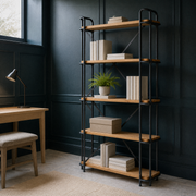 Blue-green library | ladder bookcase styled with art books and archival boxes under cool side-window light