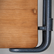 Material close-up | honey fir shelf grain and rounded edge beside subtly pebbled charcoal iron