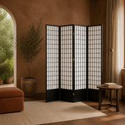 Terracotta room | black four-panel divider beside an arched garden opening, olive tree, and rust ottoman