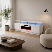 Angle | warm-white living room three-quarter view of the high-gloss white fireplace TV stand with window, plant, chair and coffee table