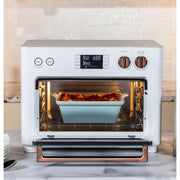 Kitchen | The oven positioned on a kitchen counter beside a cookbook and fresh herbs in a vase