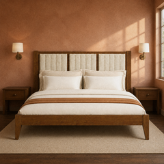 Room 3 | Straight-on bedroom view of the walnut bed and channel-tufted headboard against a clay wall with sconces