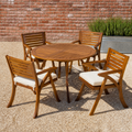 In the courtyard | round acacia table and four chairs on pale gravel by a brick wall