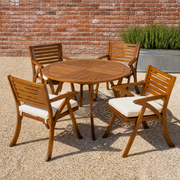 In the courtyard | round acacia table and four chairs on pale gravel by a brick wall