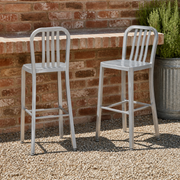 In a room | both stools at an outdoor counter on a gravel courtyard, brick wall and rosemary planter