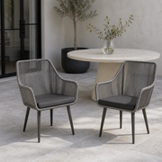 Room | two gray open-back wicker dining armchairs with gray seat cushions in a cool limewashed courtyard