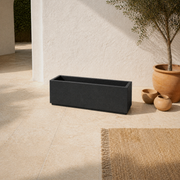 Mediterranean terrace angle | empty matte charcoal-black composite trough planter from an elevated three-quarter view